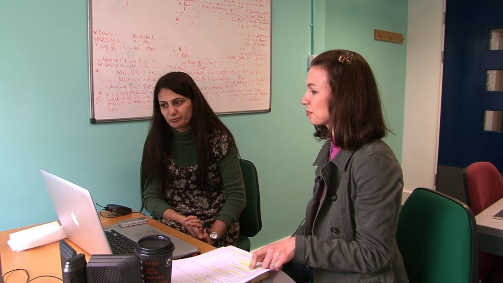 Holly views rushes and discusses filming in the Pakistani restaurant with project collaborator Saba, who helps translate Urdu to English.