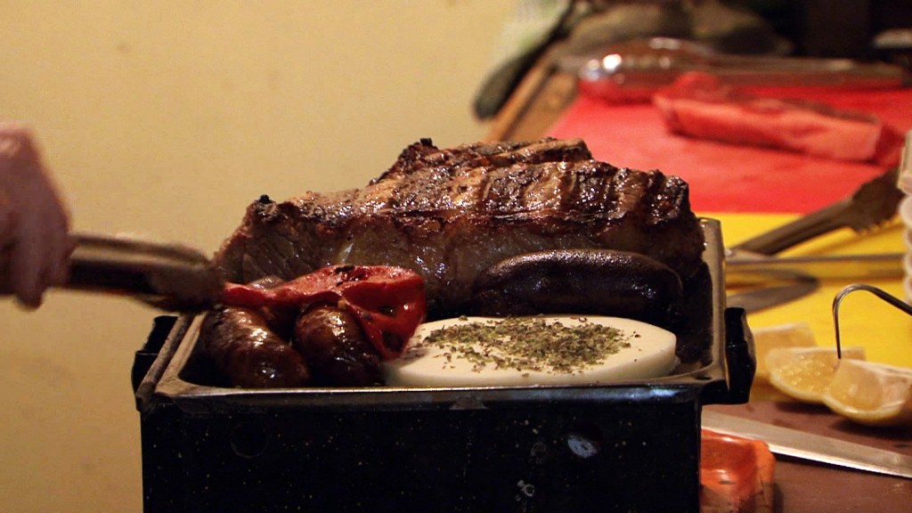 A parrillada (brazier) being prepared with steaks, sausages, blood sausage, provolone cheese and a bell pepper in the Argentinian restaurant.